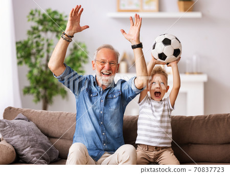 Excited grandfather and grandson watching football match on TV. 70837723