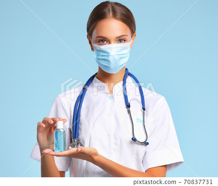 Female doctor in mask showing sanitizer. 70837731