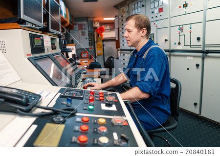 Marine engineer officer controlling vessel engines and propulsion in engine control room Marine engineer officer controlling vessel engines and propulsion in engine control room 70840181