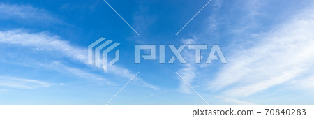 Translucent cirrus cloud stripes float slowly high in a bright blue sky on a sunny day. Translucent cirrus cloud stripes float slowly high in a bright blue sky on a sunny day. 70840283