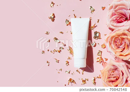 Natural organic cosmetic packaging mockup, pieces of golden paper and pink roses on pastel pink table. Blank white tube design mockup, top view. Spa cosmetic product. Natural organic cosmetic packaging mockup, pieces of golden paper and pink roses on pastel pink table. Blank white tube design mockup, top view. Spa cosmetic product. 70842548