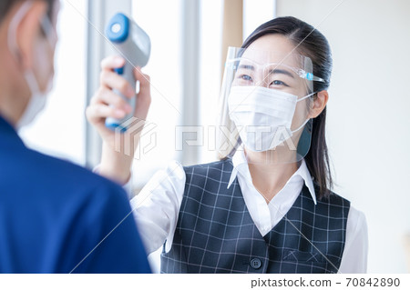 Female staff measuring temperature with a medical non-contact thermometer 70842890