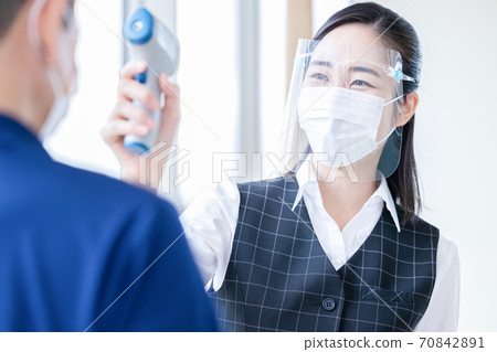 Female staff measuring temperature with a medical non-contact thermometer Female staff measuring temperature with a medical non-contact thermometer 70842891