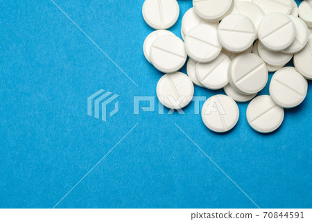group of white pills or tablets on blue background group of white pills or tablets on blue background 70844591