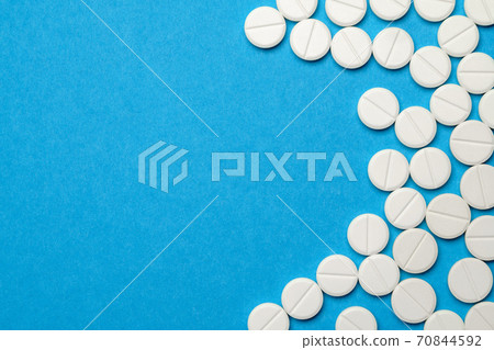 group of white pills or tablets on blue background group of white pills or tablets on blue background 70844592