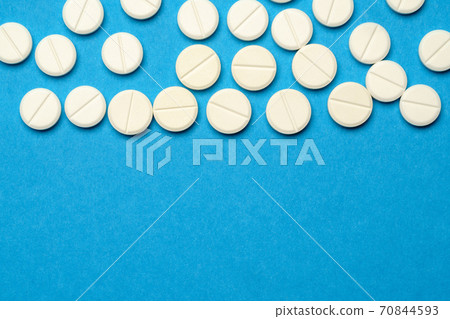 group of white pills or tablets on blue background group of white pills or tablets on blue background 70844593