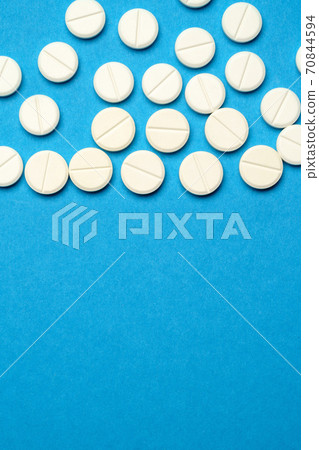 group of white pills or tablets on blue background group of white pills or tablets on blue background 70844594