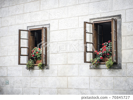Wooden windows with flowers in the old sandstone house 70845727