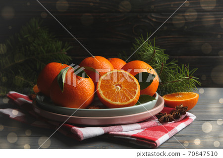 Plates with mandarins, pine branches, napkin and cinnamon on wooden background 70847510