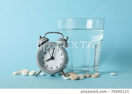 Glass of water, alarm clock and pills on blue background 70848123