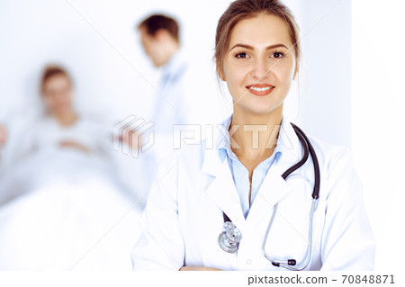 Female doctor smiling on the background with patient in the bed and two doctors 70848871