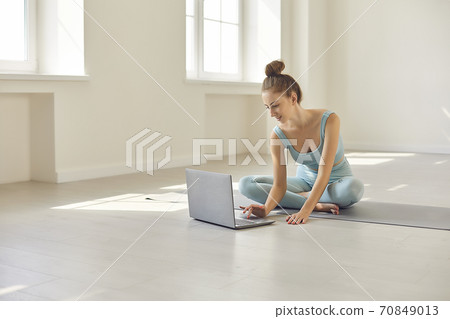 Girl turning on laptop for watching yoga video lesson online in studio 70849013