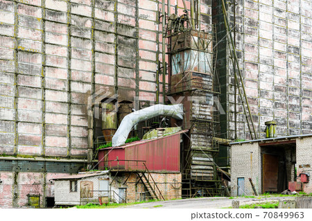 old factory building wall with auxiliary buildings and various pipes 70849963