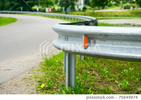asphalt road bend with a metal protection barrier in the foreground asphalt road bend with a metal protection barrier in the foreground 70849974