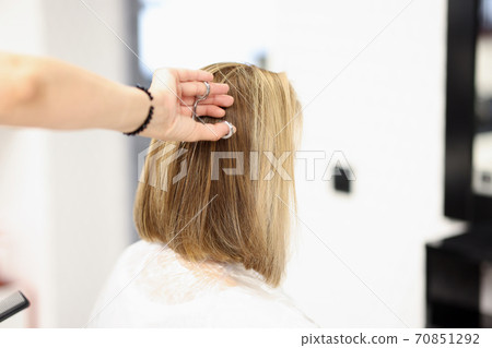 Woman in hairdressing salon cuts her hair Woman in hairdressing salon cuts her hair 70851292