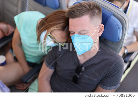 Man and woman in medical protective masks are sleeping in aircraft cabin 70851300