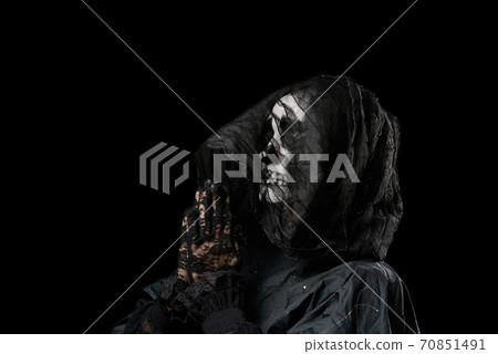 woman with a make-up skeleton stands in black clothes and a transparent hood, hands are folded in a prayer pose 70851491