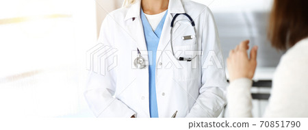 Unknown woman-doctor communicating with female patient in sunny clinic. Physician checks medical history record and exam results, close-up 70851790