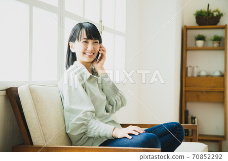 A woman operating a smartphone at home 70852292