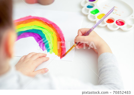 Child's hands drawing rainbow. 70852483