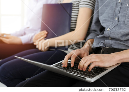 Group of casual dressed business people sitting in a line while waiting for a job interview in sunny office Group of casual dressed business people sitting in a line while waiting for a job interview in sunny office 70852762