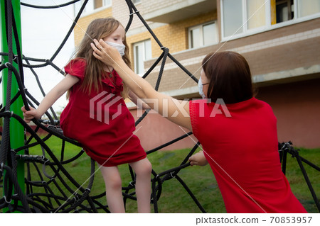 Child and mom in medical mask on a walk. Family wearing face mask 70853957