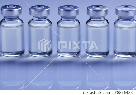 Vials with liquid drug as vaccine dose flu shot for injection treatment on medical table. Vaccination or immunization care concept background. Vials with liquid drug as vaccine dose flu shot for injection treatment on medical table. Vaccination or immunization care concept background. 70856488