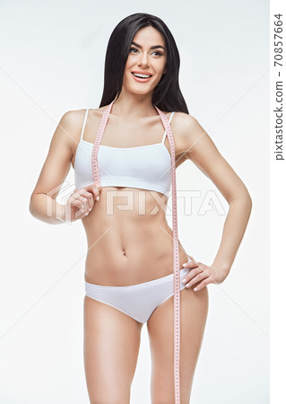Slim tanned woman's body isolated on white background - waist measurement 70857664