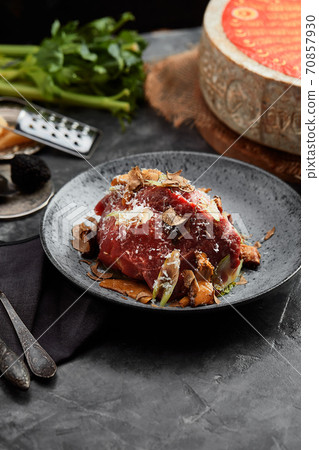 A plate of salad with beef roast beef, onions, arugula, pepper and tomatoes on a black table. Top view. A plate of salad with beef roast beef, onions, arugula, pepper and tomatoes on a black table. Top view. 70857930