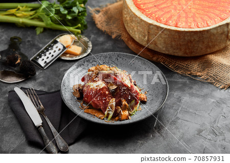 A plate of salad with beef roast beef, onions, arugula, pepper and tomatoes on a black table. Top view. 70857931