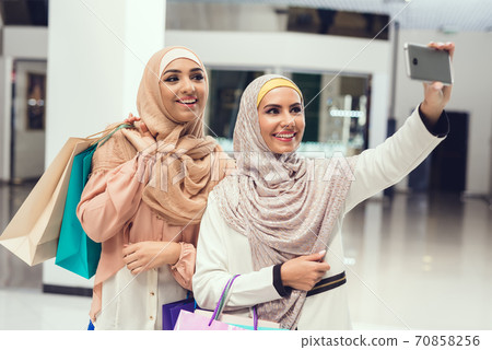 Young Arabian Women Taking Selfie in Modern Mall. Young Arabian Women Taking Selfie in Modern Mall. 70858256