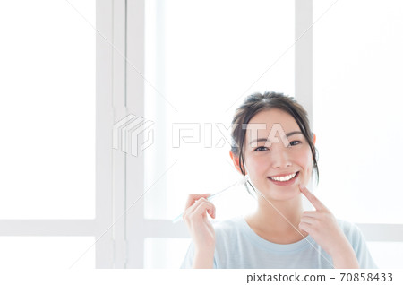A young woman brushing a tooth A young woman brushing a tooth 70858433