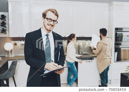Couple stands in kitchen while salesman smiles. 70858459