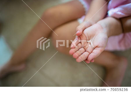 Unrecognizable small girl indoors, loosing baby tooth. 70859236