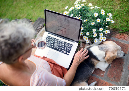 Top view of senior woman architect with laptop working outdoors in garden, home office concept. 70859371