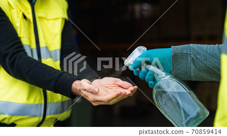 Unrecognizable warehouse workers disinfecting hands, coronavirus concept. Unrecognizable warehouse workers disinfecting hands, coronavirus concept. 70859414