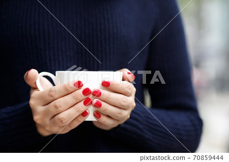 A woman holding a hot cup of coffee at the coffee shop 70859444