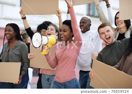 Happy protestors walking by street with blank placards and megaphone Happy protestors walking by street with blank placards and megaphone 70859524
