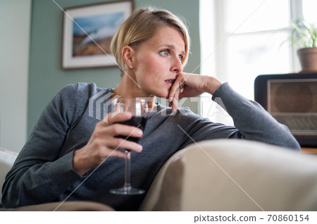 Depressed woman with wine indoors at home, mental health and alcohol addiction concept. Depressed woman with wine indoors at home, mental health and alcohol addiction concept. 70860154