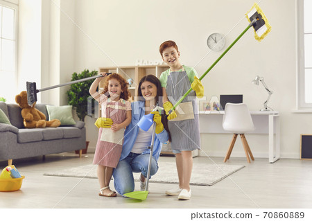 Happy mom and kids with floor mops and dustpan smiling and looking at camera after a big clear-out 70860889