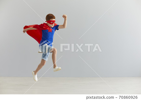 Little boy in a superhero costume jumped on a gray background. Superhero child. Kids costume. 70860926