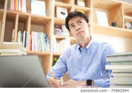 A young man pondering in front of a PC A young man pondering in front of a PC 70862064