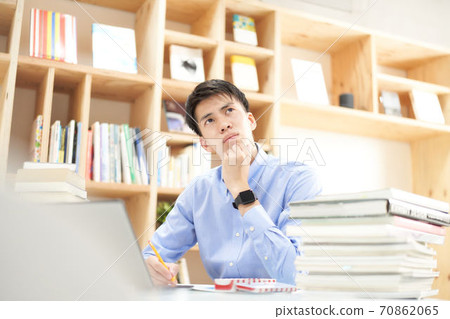 A young man pondering in front of a PC A young man pondering in front of a PC 70862065