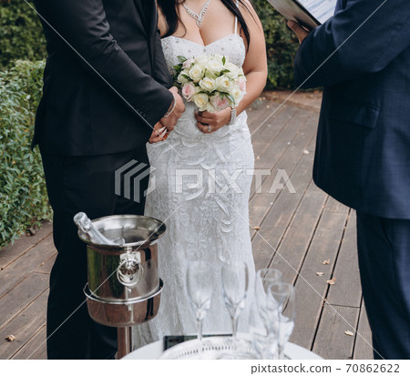 Bridal couple having their official wedding ceremony next to a registrar. Bridal couple having their official wedding ceremony next to a registrar. 70862622
