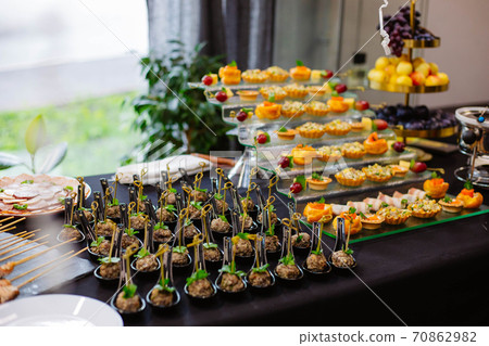 Canape, appetizers, on the table, buffet menu, European cuisine, shrimp, mini burger on a wooden background. 70862982