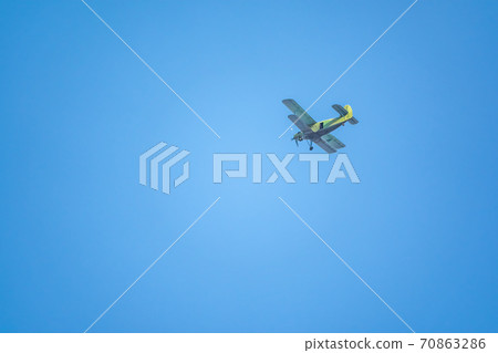 Retro green biplane plane in the blue sky Retro green biplane plane in the blue sky 70863286