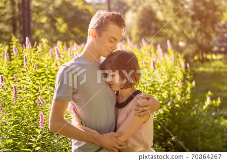 Young man hugs woman in public park. Young man hugs woman in public park. 70864267