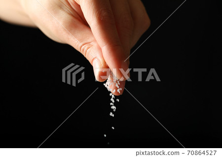 Female hand adding salt on black background Female hand adding salt on black background 70864527
