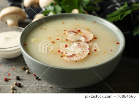Concept of tasty lunch with bowl of mushroom soup on gray background Concept of tasty lunch with bowl of mushroom soup on gray background 70864566