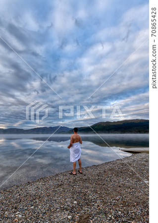 Man standing by water ready to go swimming Man standing by water ready to go swimming 70865428